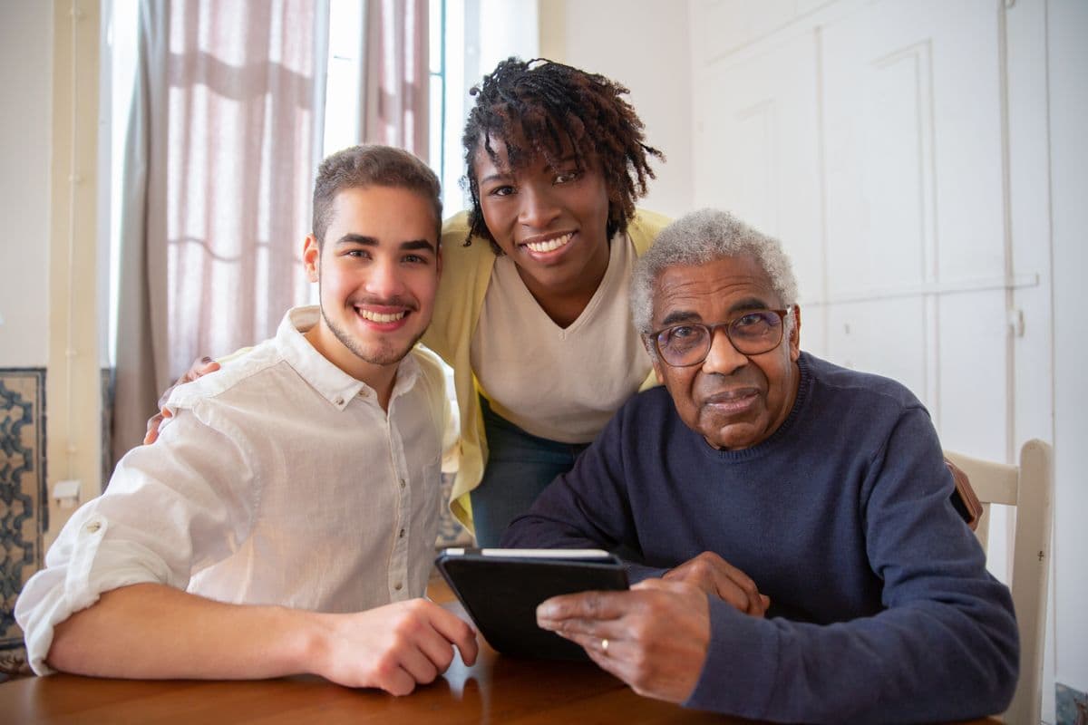 A support worker and an older man laughing together over a laptop