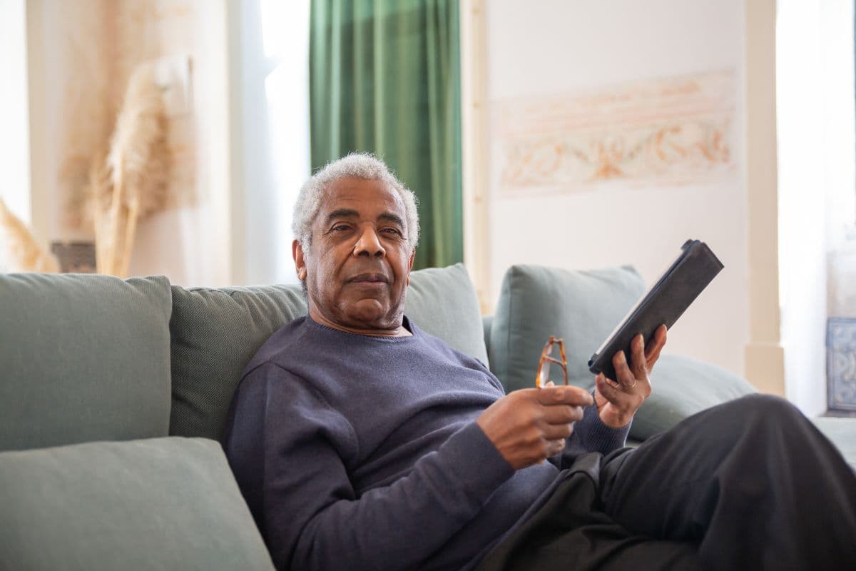 An older man reading about his NDIS plan on a tablet at home